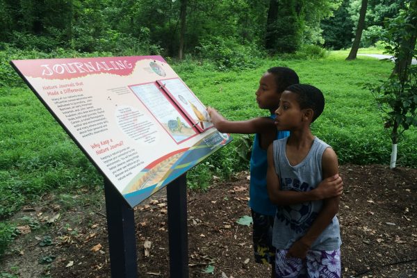 Two young boys read an informative trail marker along the Schuylkill River Trail within the Schuylkill River Heritage Area.